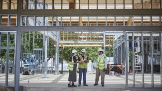 Three people reviewing plans at a construction site
