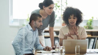 three people working together on a computer