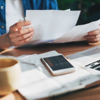 Person looking at paper and calculating salary with a calculator