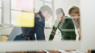 people working at a table on the other side of a window