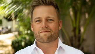 Head shot of a man with short blonde hair wearing a light shirt