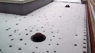Roof fasteners on snowy roof show thermal bridging