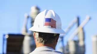 a man wears a white hard hat with an American flag sticker