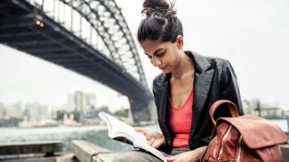 Woman reading under a bridge