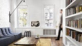 New York studio apartment featuring divider wall with book shelf on one side, appliances on the other.