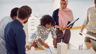 group of diverse architects talking and looking at a building model on a table