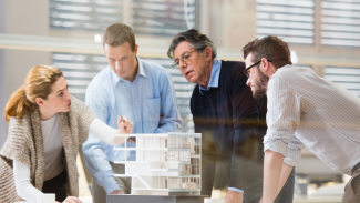 Four architects around a table discussing a model