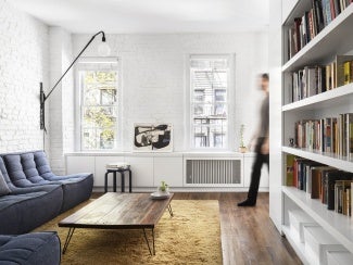 New York studio apartment featuring divider wall with book shelf on one side, appliances on the other.