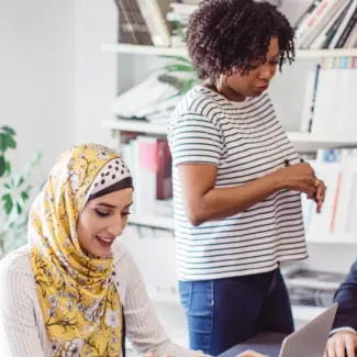 A diverse group of people collaborating around a laptop