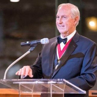 man in tuxedo standing in front of podium