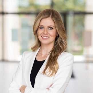 Headshot of a woman with long blonde hair wearing a white jacket. 