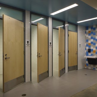 hallway with entry to 4 single-user bathrooms, and external sink near them