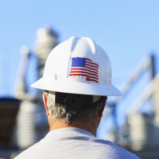 a man wears a white hard hat with an American flag sticker