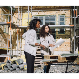 two female architects review plans on a job site