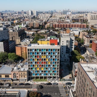 Gridded concrete façade with colorful painted steel panels stands out in South Bronx