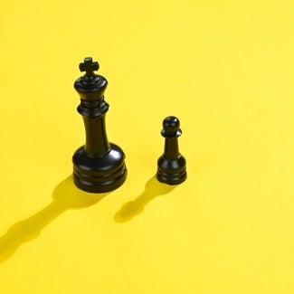 black king and pawn chess pieces on yellow background 