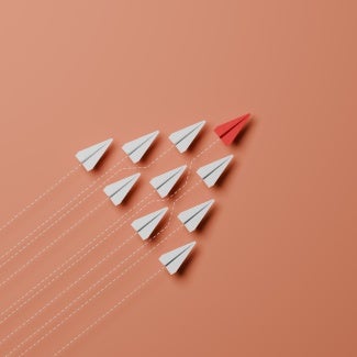 photo illustration red paper airplane leading formation of white paper airplanes