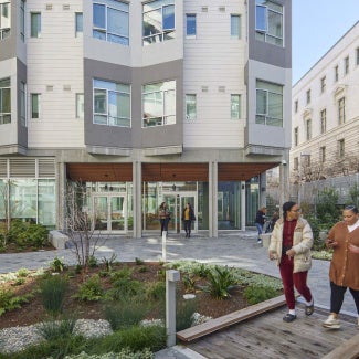 two women walking in front of apartment complex with landscaping and common space
